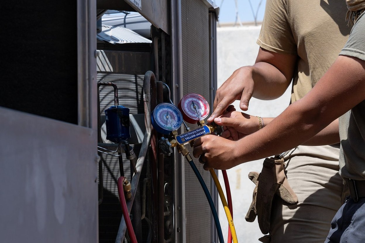 An HVAC technician servicing an outdoor air conditioning unit