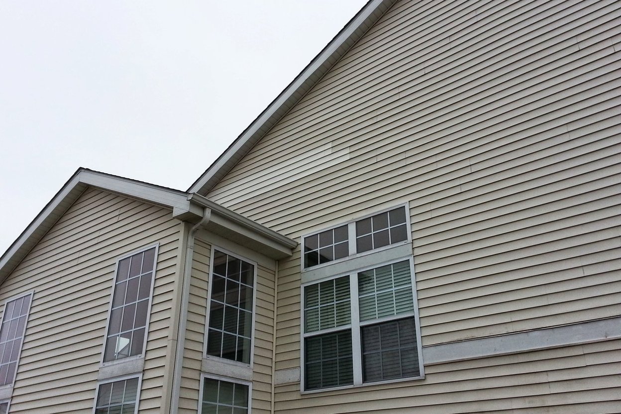 Tan vinyl siding on the gable of a two-story home after a repair