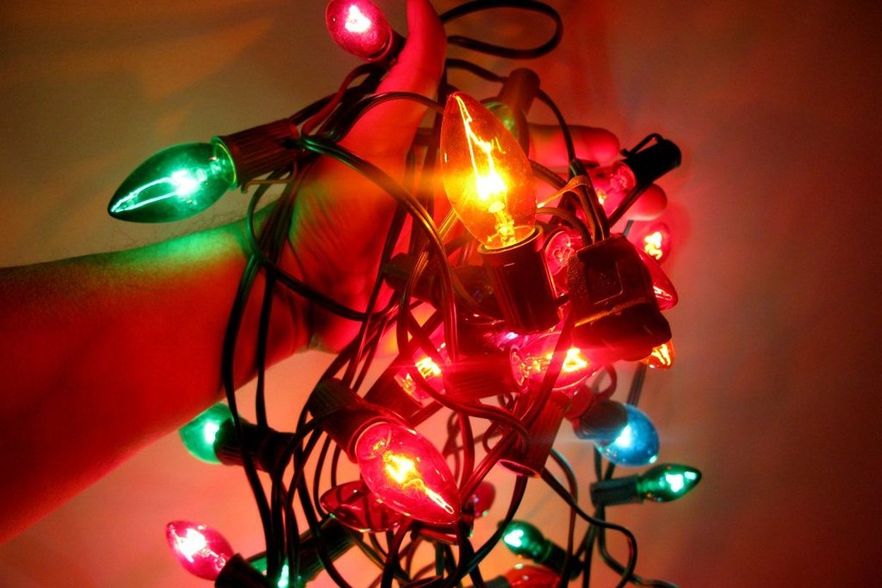 Electrician or handyman inspecting an old frayed holiday light cord for damage before storage or reuse.