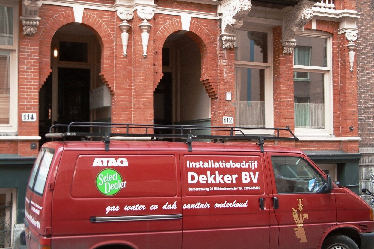 A row of branded HVAC and plumbing service vans parked outside a contractor's shop on a fall morning