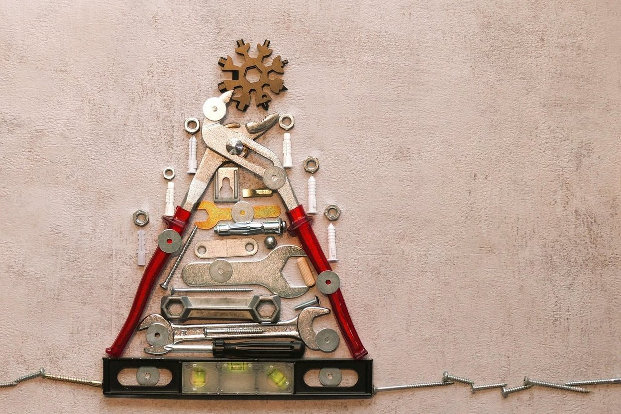 Christmas tree made of tools and hardware on a textured wall.